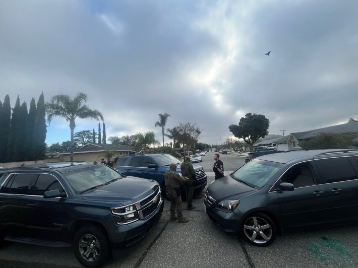 Two masked ICE agents are speaking a Simi Valley Police Officer in between their vehicles and Martinez's minivan.