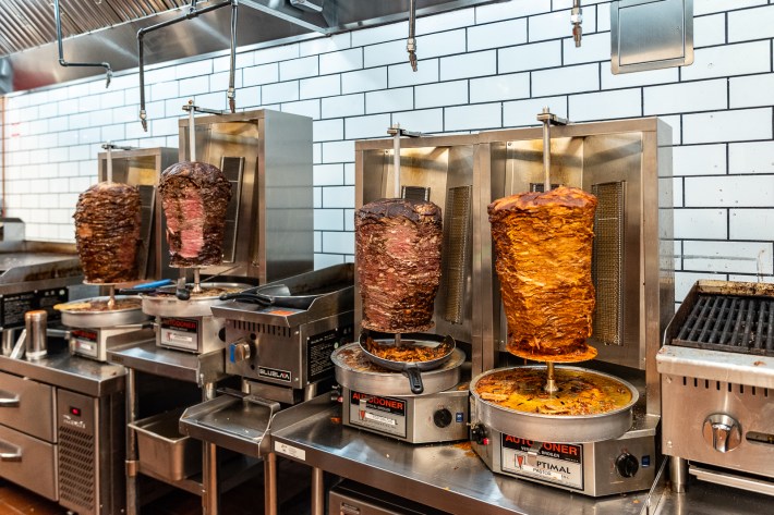 Four trompos at a taqueria, three of them with beef and the last one on the left with pork