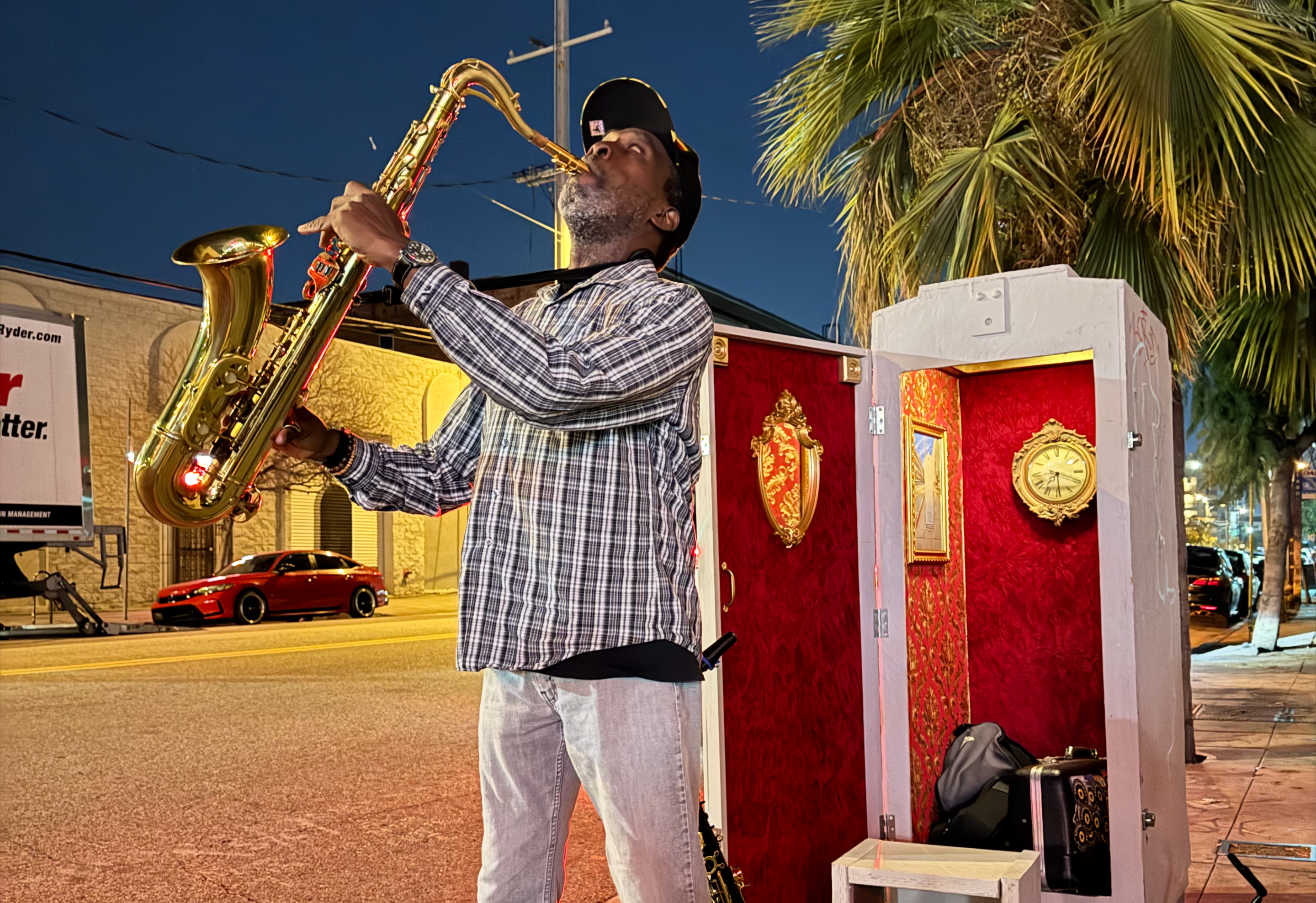 a man plays the saxophone in front of an electrical box theater