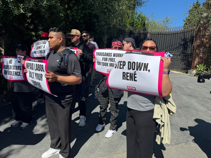 Organizers with One Fair Wage protest the new Noma popup in Silver Lake. They hold signs that say "STEP DOWN RENE" and UNPAID LABOR BUILT YOUR EMPIRE".
