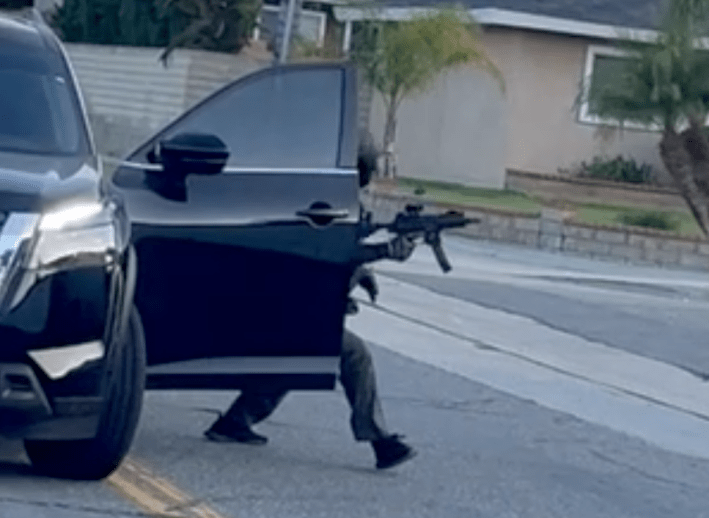 a man leaves a car carrying a gun