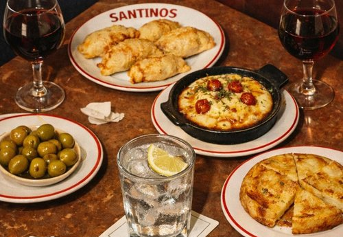 A table set with empanadas, tortilla espanola, olives, and provoleta