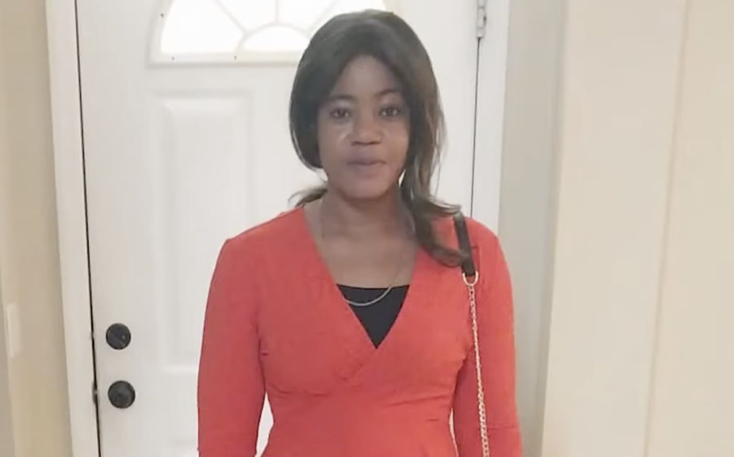 a woman standing in front of a door, smiling softly