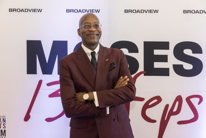 a man poses in front of a backdrop