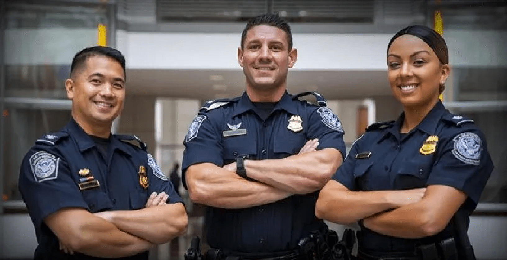 Three U.S. Customs and Border Patrol agents posing in their navy blue uniform.