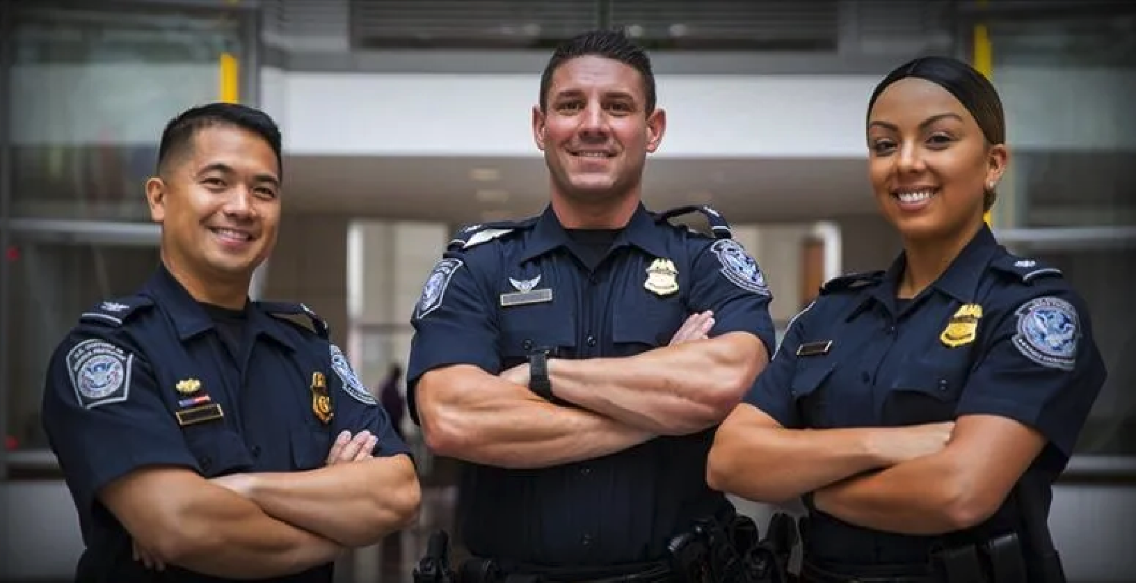 Three U.S. Customs and Border Patrol agents posing in their navy blue uniform.