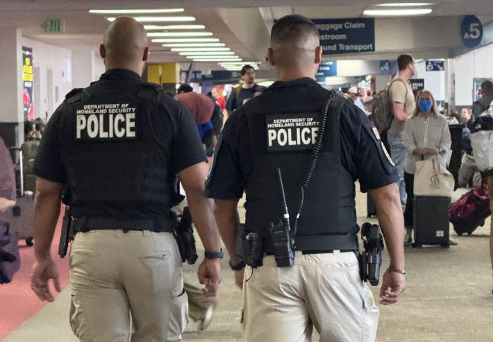 Two DHS Police officers with TSA walking through an airport terminal
