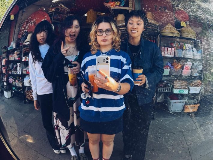 four bandmates posing in a mirror outside