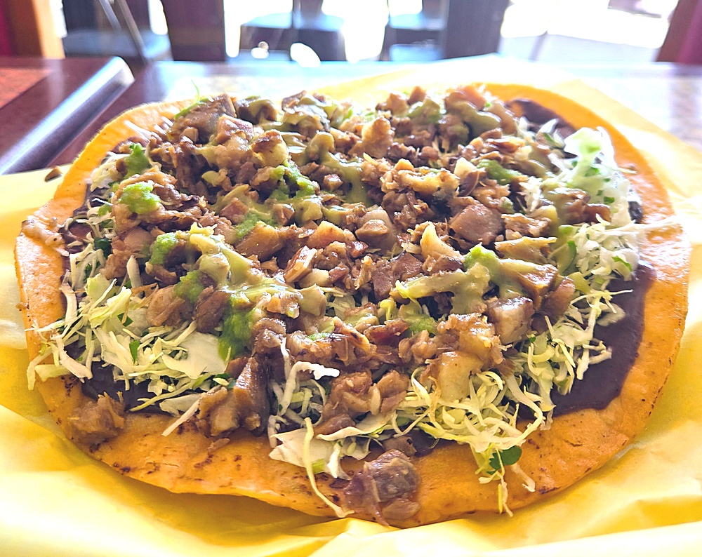 A tostada spread with black beans, cabbage, and cabeza de puerco.