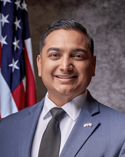 Arturo Flores stands in front of an American flag.