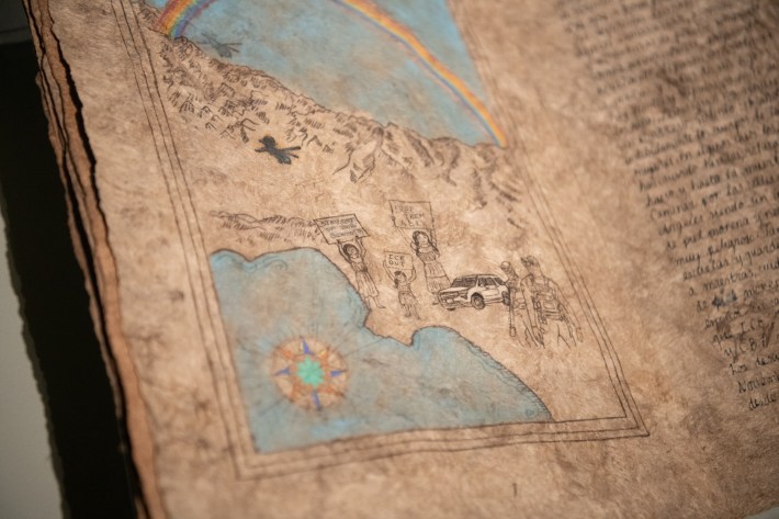 "Book 13" exhibit by Sandy Rodriguez at The Huntington, featuring a closeup of book pages made with amate paper and hand-processed pigments to depict ICE agents and protesters