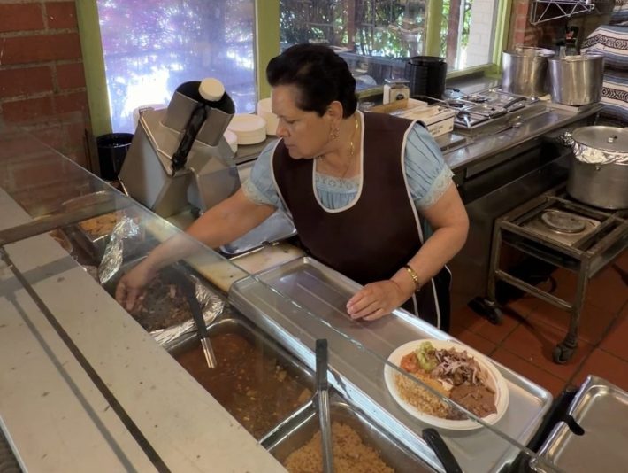 a woman in an apron prepares a plate of food in a restaurant