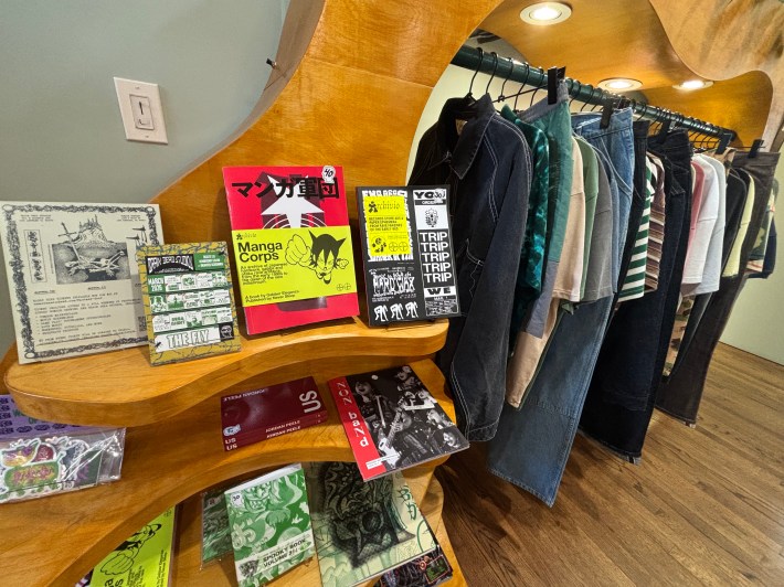 books and merch on shelves next to a clothing rack