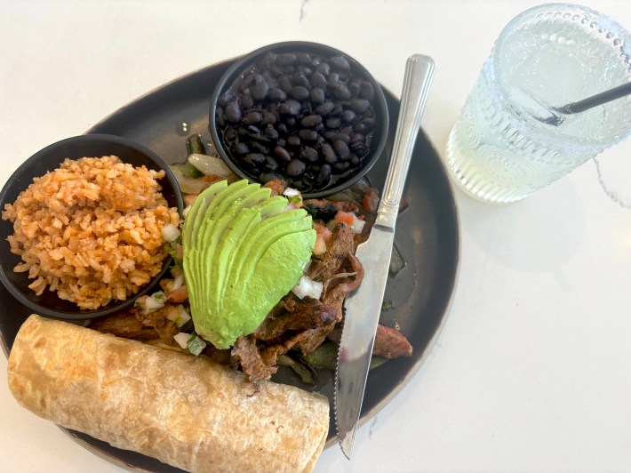 a plate of ribeye fajitas with rice and black beans on the side