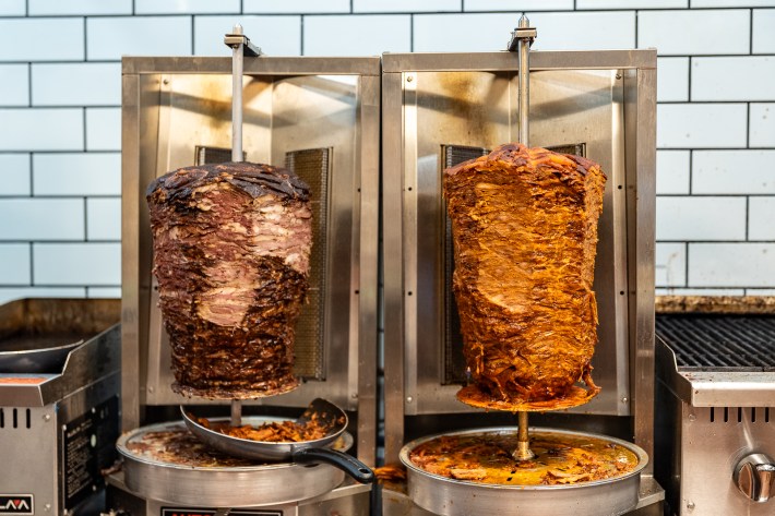 two trompos packed with meat, spinning on a vertical spit