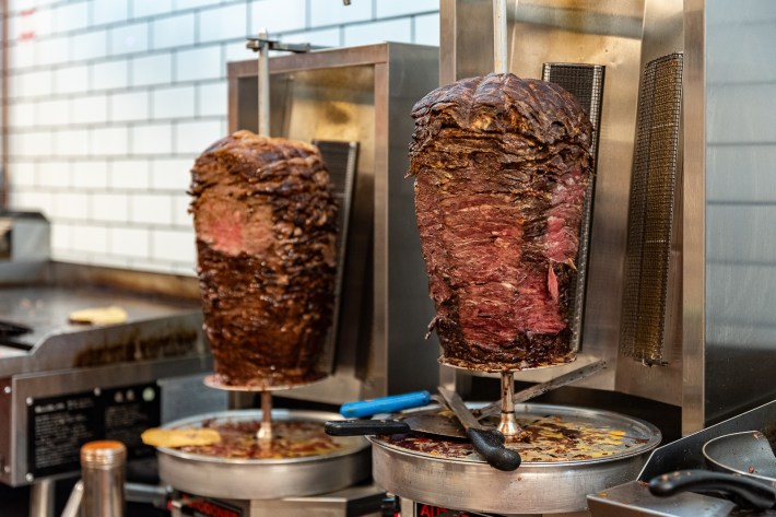 two trompos packed with meat, spinning on a vertical spit