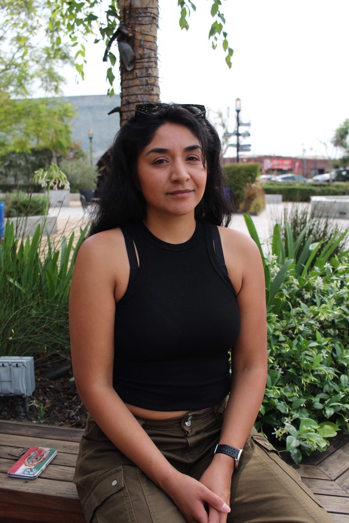 Fátima Rodriguez-Ortiz sits outside in front of green plants.