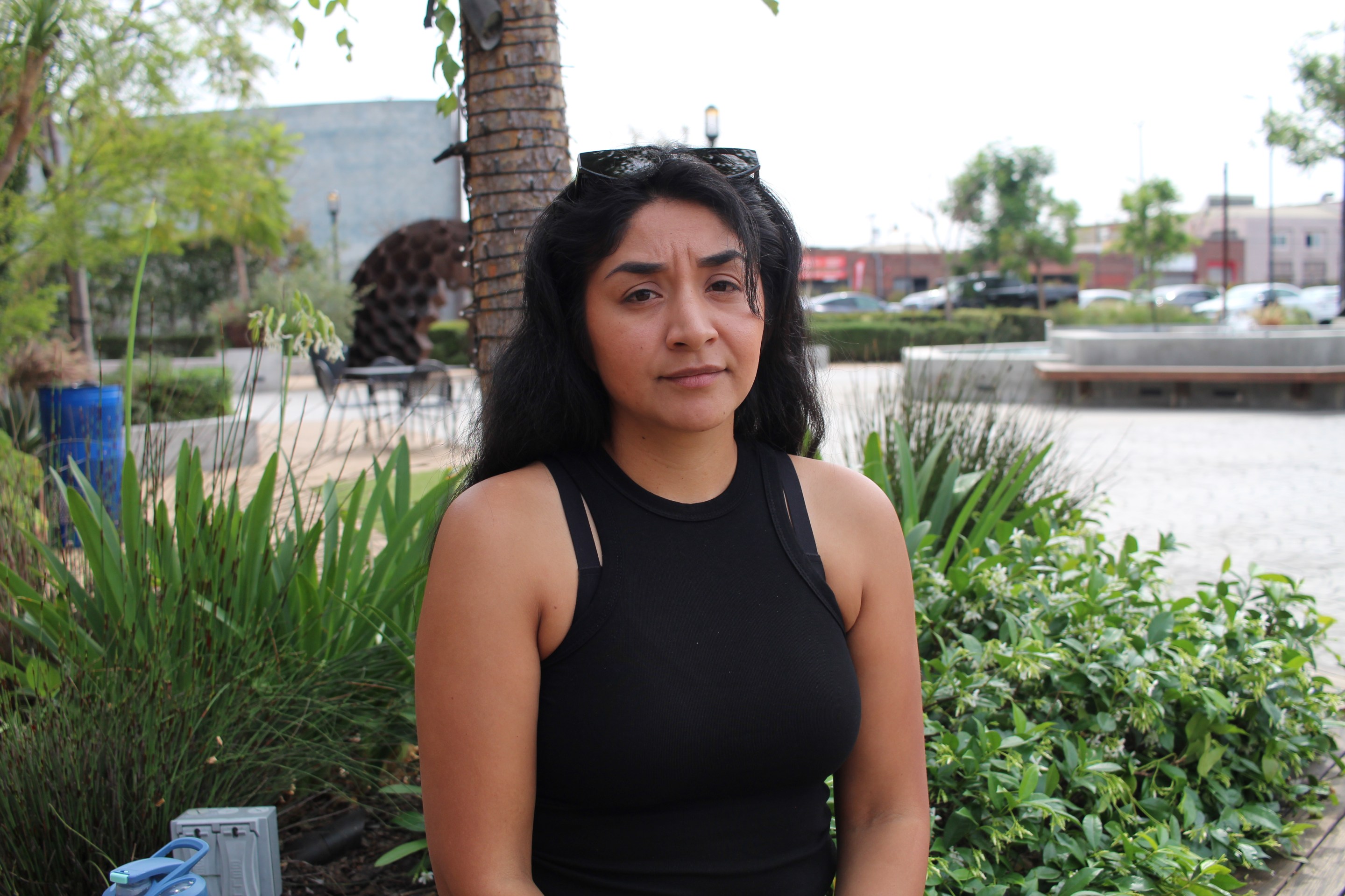 Fátima Rodriguez-Ortiz sits outside in front of some green plants.