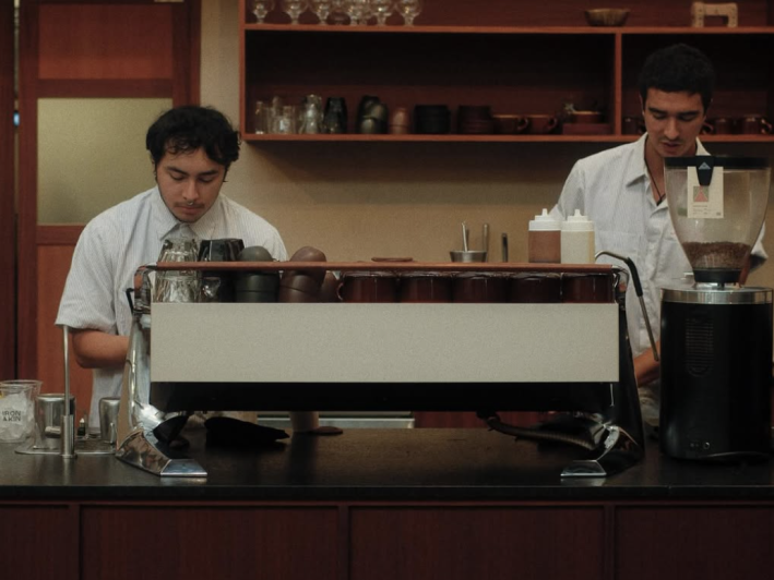 Two baristas behind an espresso machine