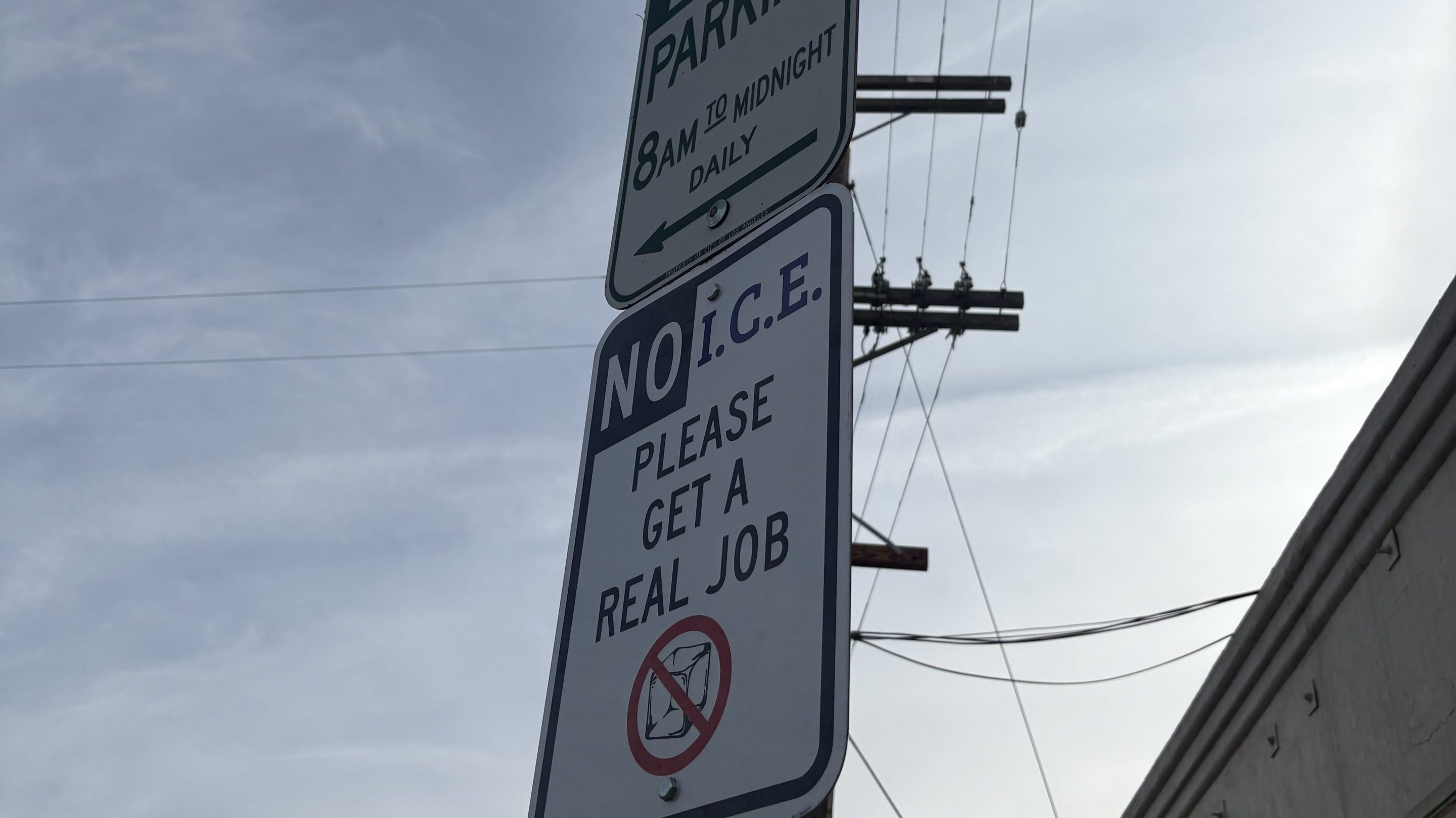 a sign in the style of a parking sign: "NO I.C.E. PLEASE GET A REAL JOB"