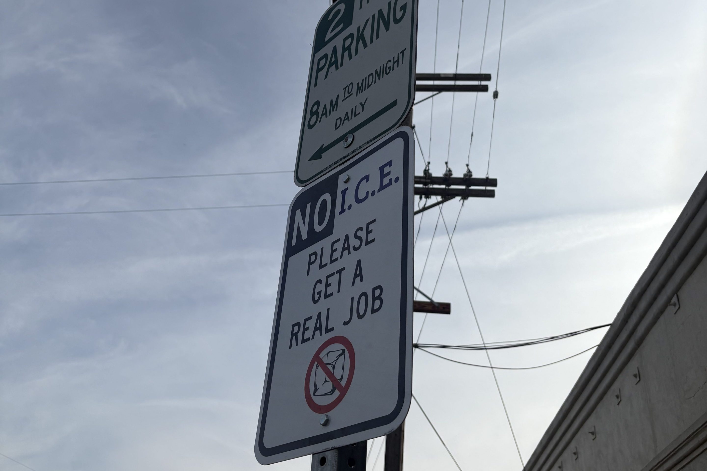 a sign in the style of a parking sign: "NO I.C.E. PLEASE GET A REAL JOB"