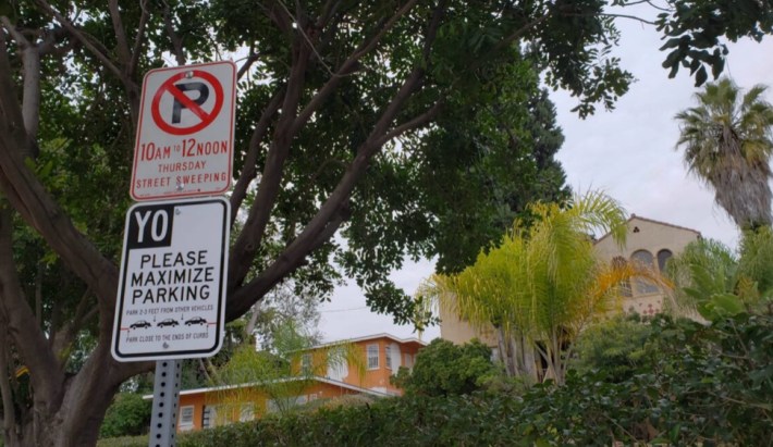an unofficial street sign reading "YO PLEASE MAXIMIZE PARKING"