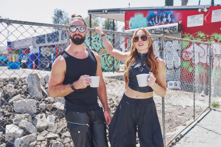 a man and woman hold coffee mugs outside