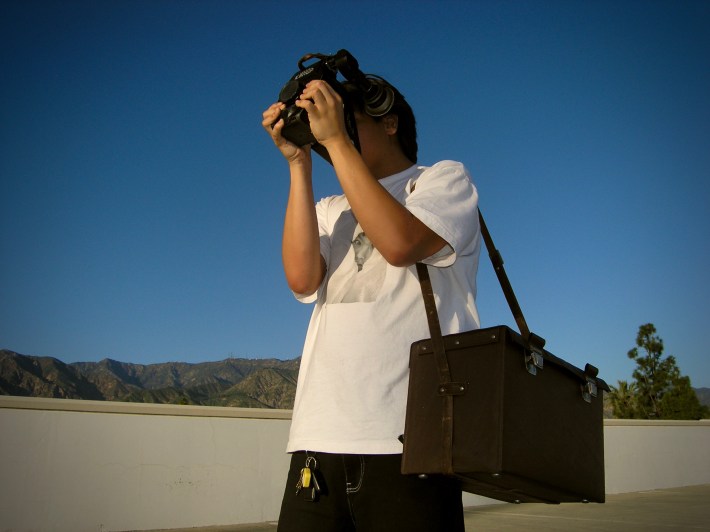 a young man uses a camera while outside