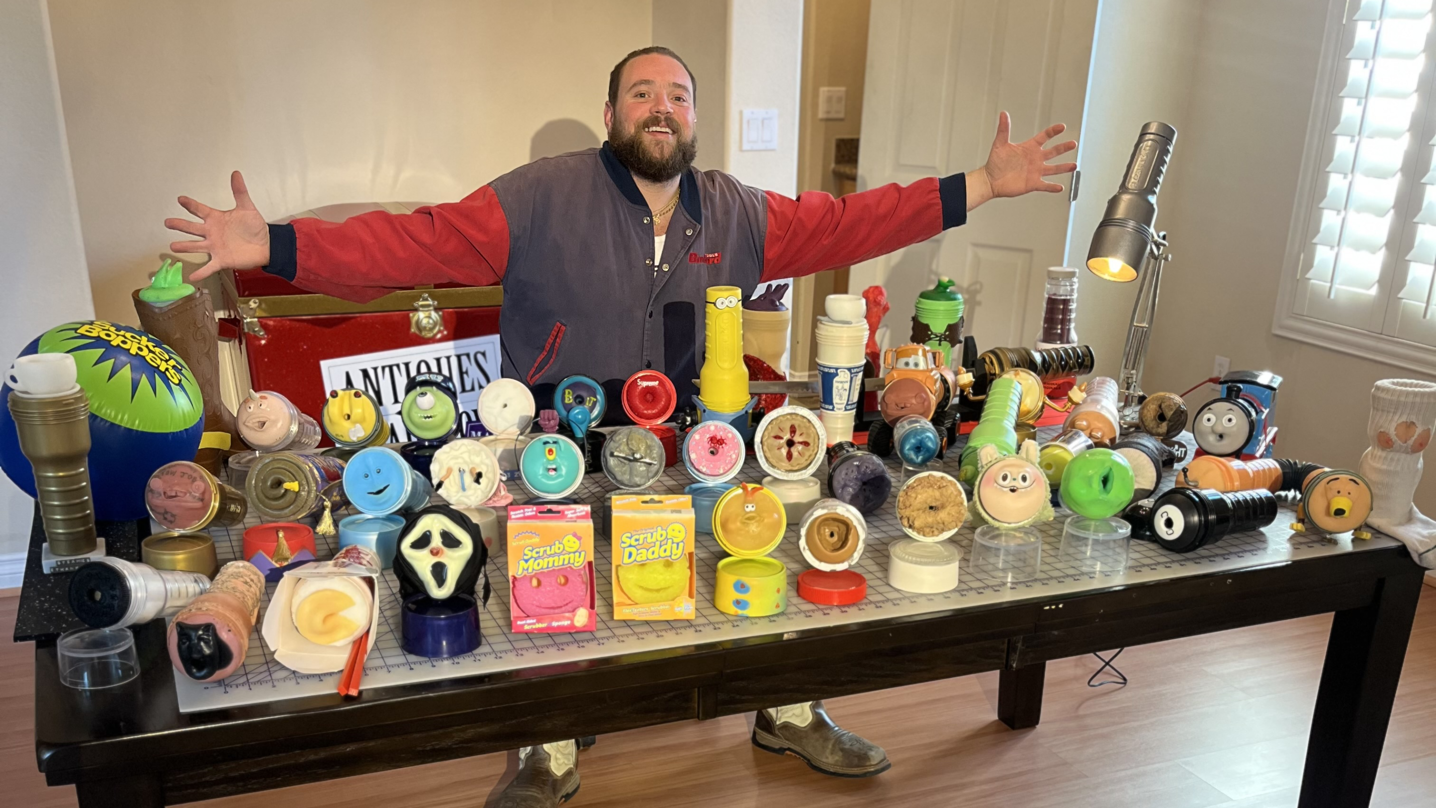 a man poses with an array of artistic sex toys