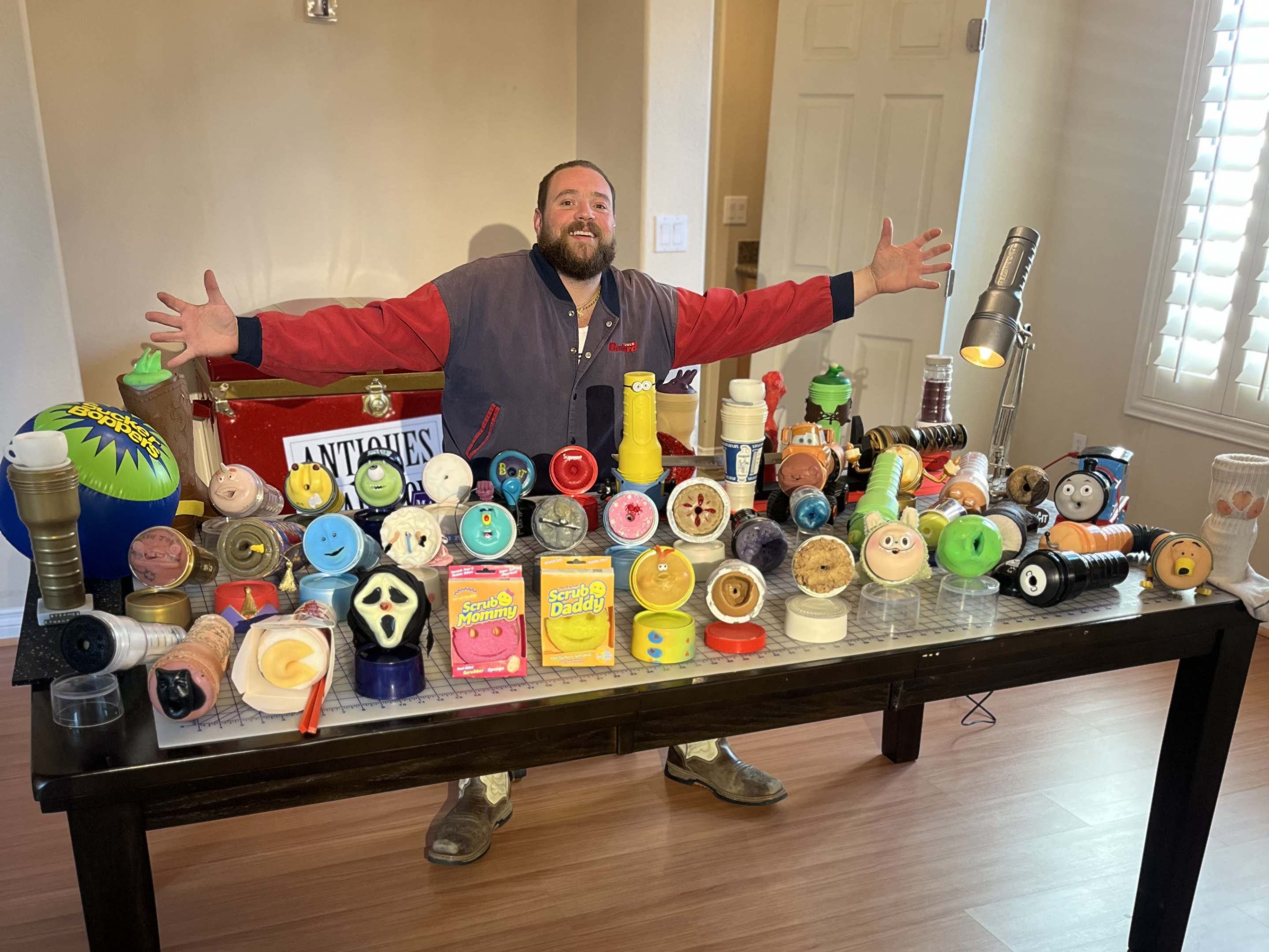 a man poses with an array of artistic sex toys