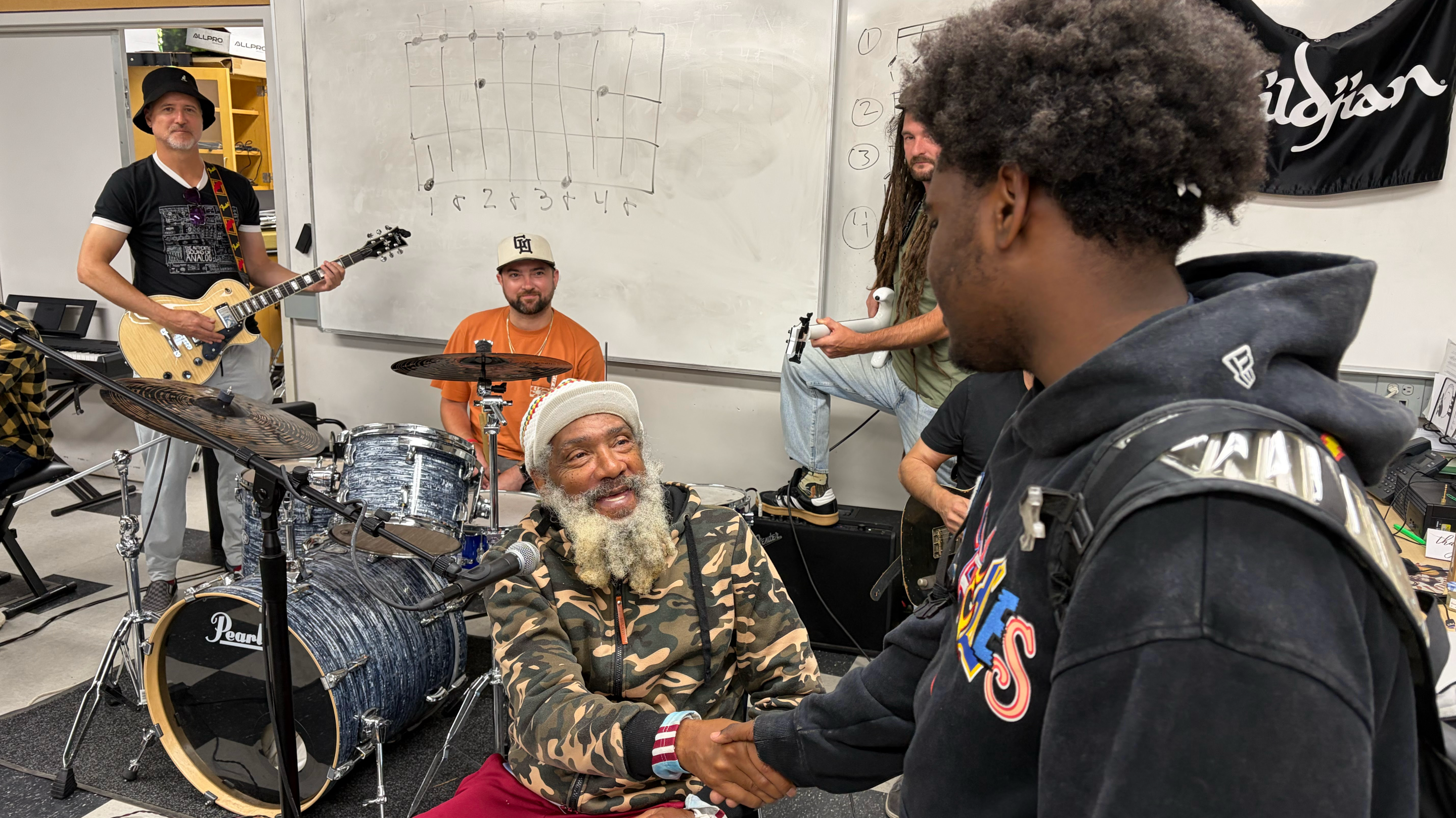 an older man shakes the hand of a young student