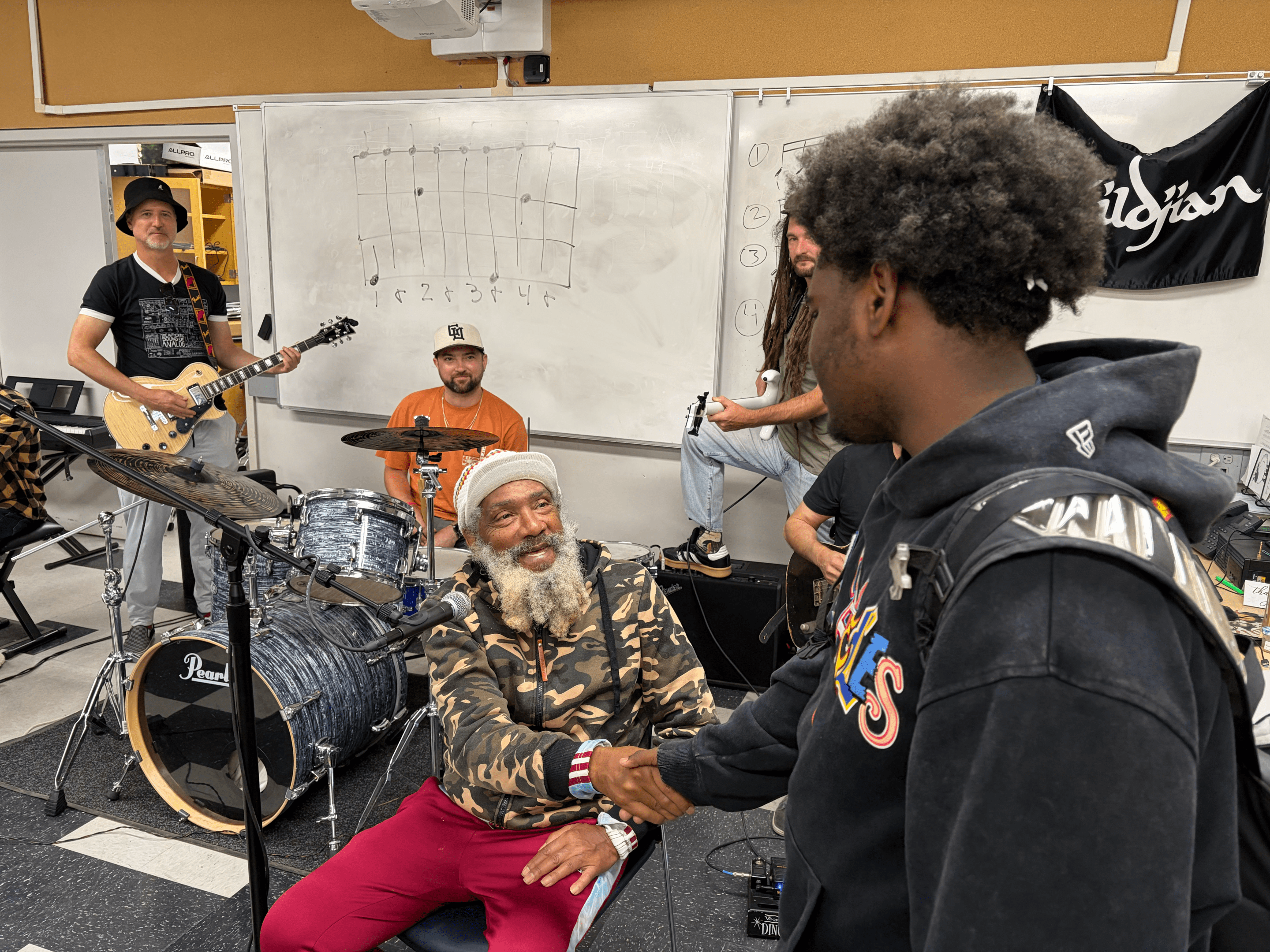 an older man shakes the hand of a young student