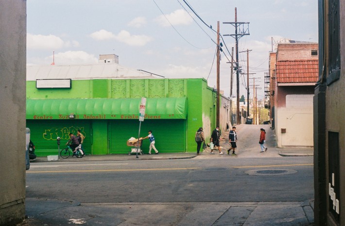 People walk past a bright green building.