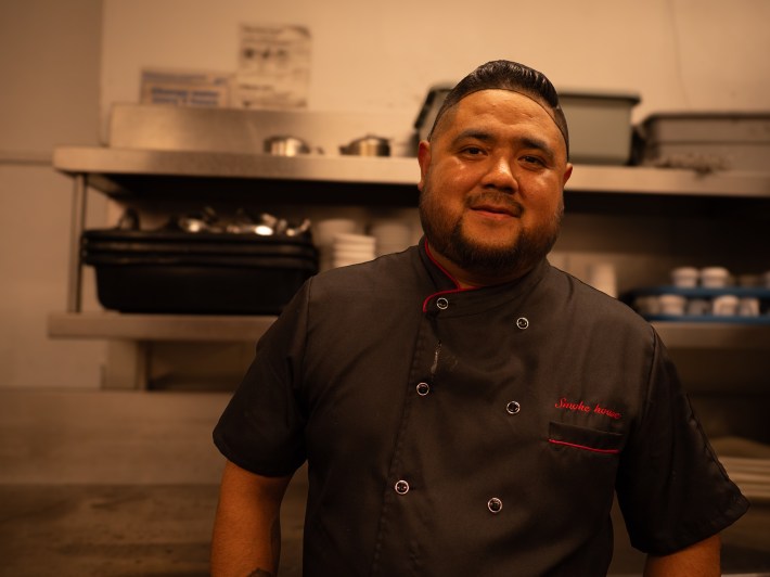 a man in a black uniform in a restaurant's kitchen
