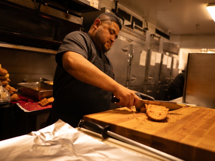 a man chops food on a wooden cutting board