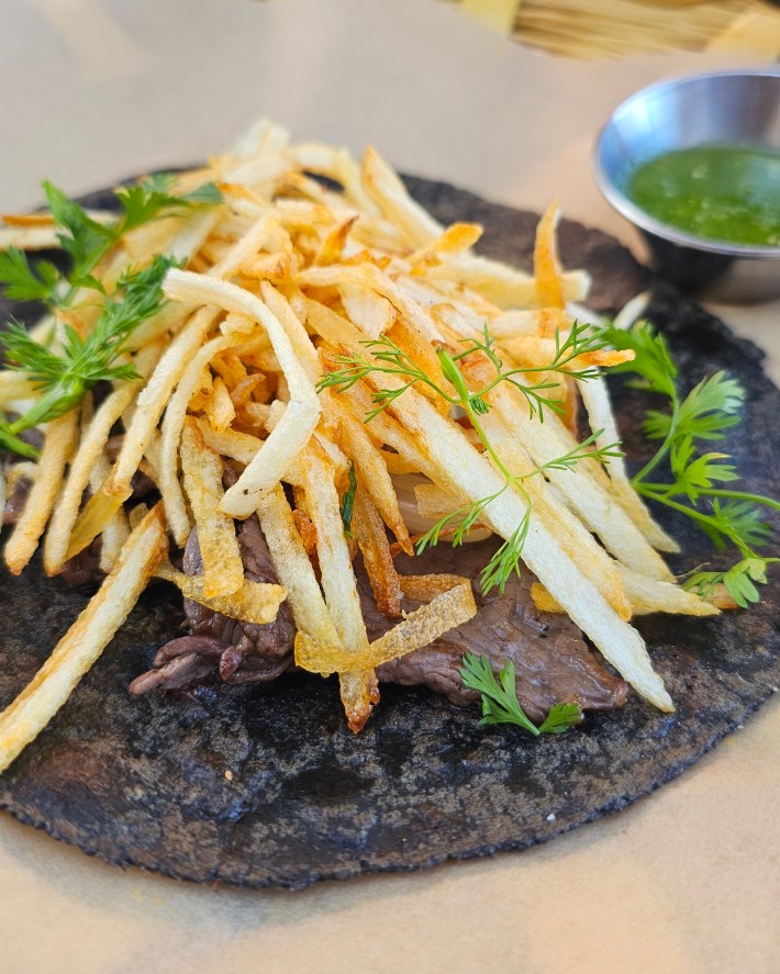 Blue corn tortilla covered in beef and fries.
