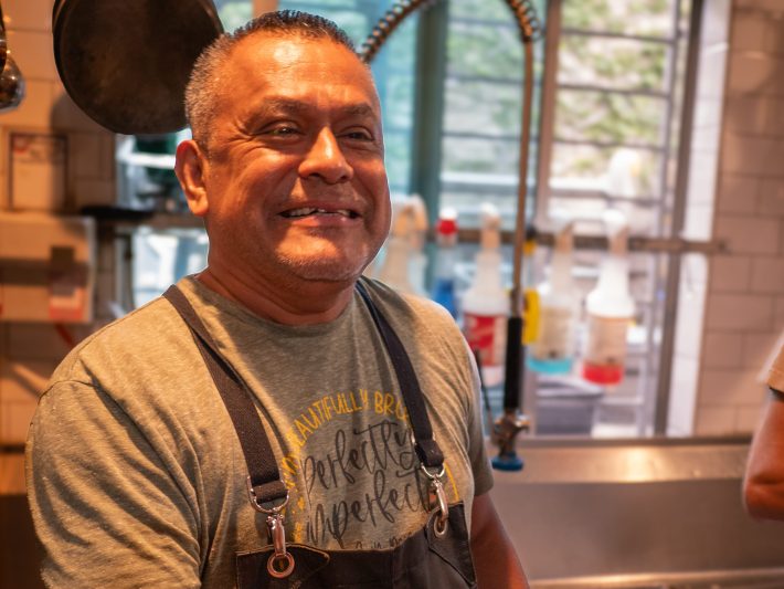 a man in an apron in front of a restaurant sink