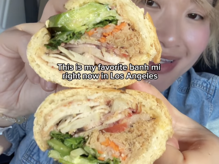 a woman holds a sandwich to show off the cross-section