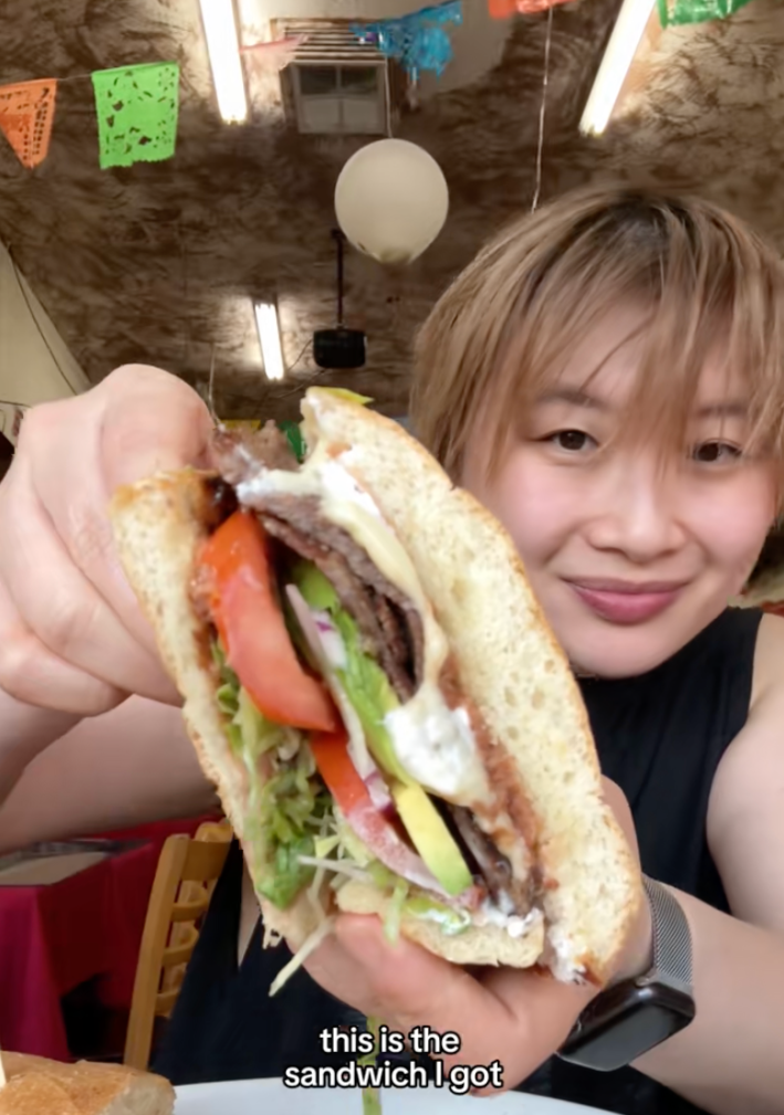 a woman holds a carne asada torta