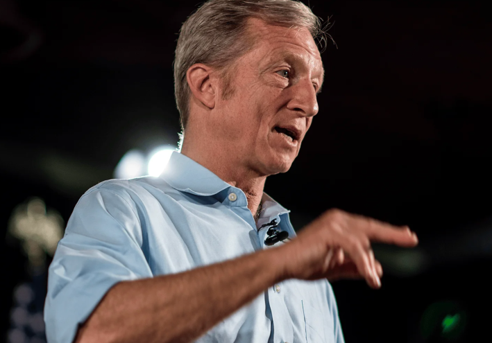 a man in a blue collared shirt speaking