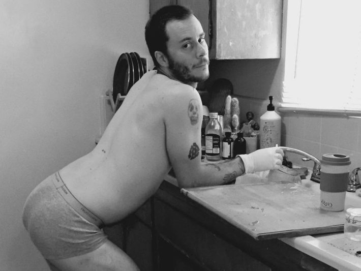 a person in only underwear leans over a sink