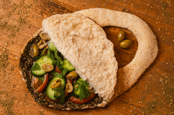 A purse-shaped flatbread known as kaake, stuffed with tomatoes, olives, cucumbers, mint, and za'atar