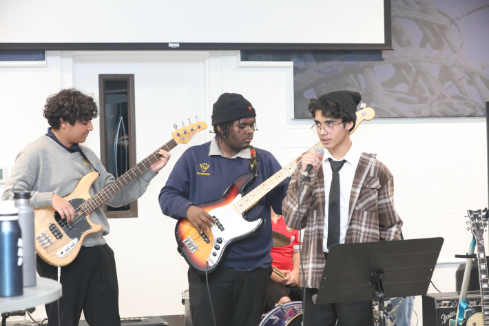 two students with guitars and one with a microphone