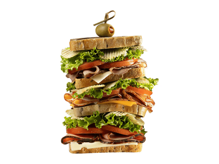 A quadruple stacked sandwich with an olive speared on top, resembling a tall sandwich from Scooby Doo