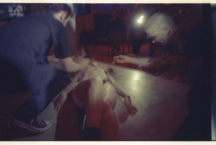 Men decorate a woman's semi-nude body with food