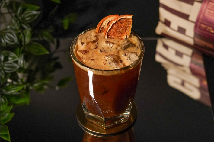 An espresso tonic in a glass topped with dried citrus