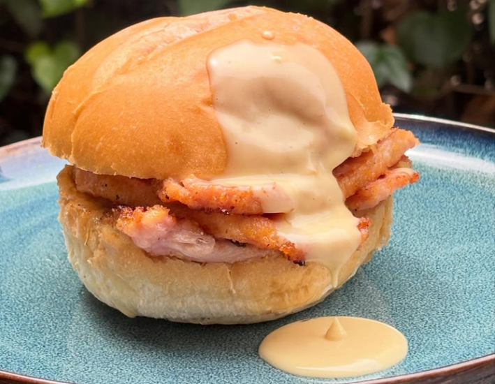 A peamal bacon sandwich, oozing with maple Dijon sauce, on a blue plate
