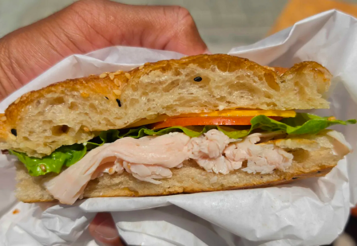 A turkey sandwich on focaccia in a man's hand