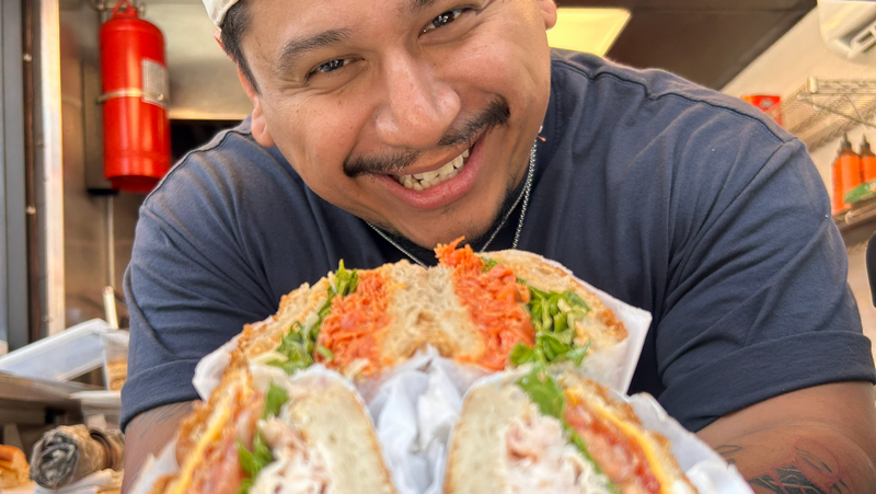 a man serving sandwiches through an open window