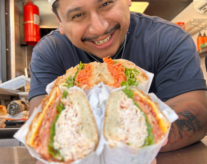 a man serving sandwiches through an open window